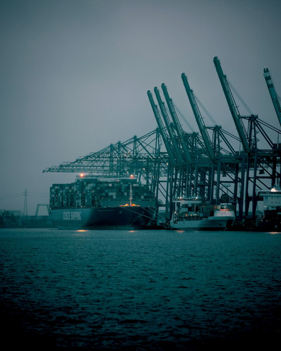Container cranes and a cargo ship at a port at dusk